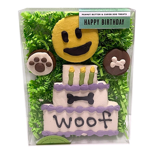front view of Happy Birthday box. Yellow frosted round smiley face treat, 2 small round treats with pawprint and bone "frosting" , large white "frosted" 3 tier cake, text says "woof"