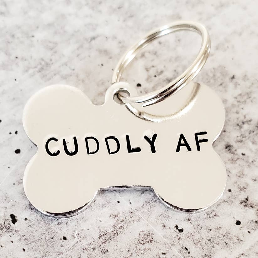 silver aluminum bone shaped dog tag with text "CUDDLY AF"